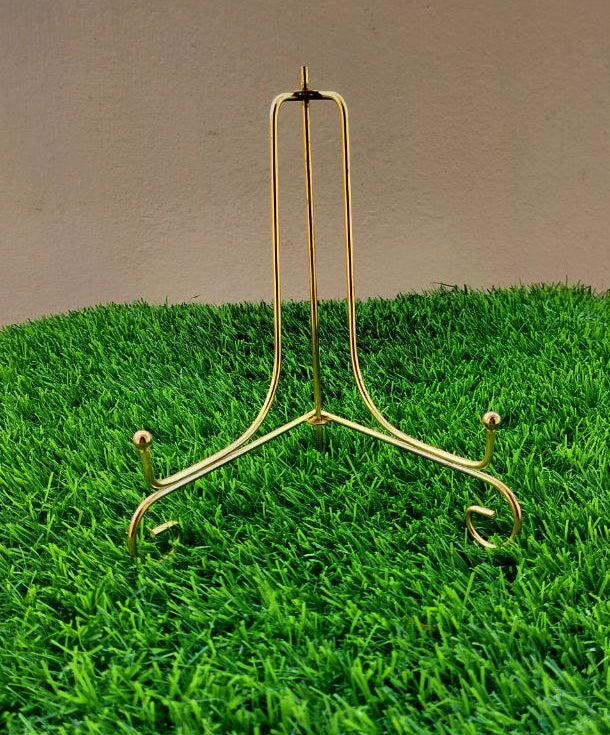 Gold metal stand on a green grass-like surface with a plain background